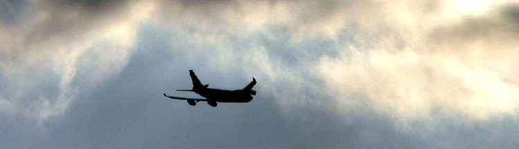 An airplane flies by clouds.